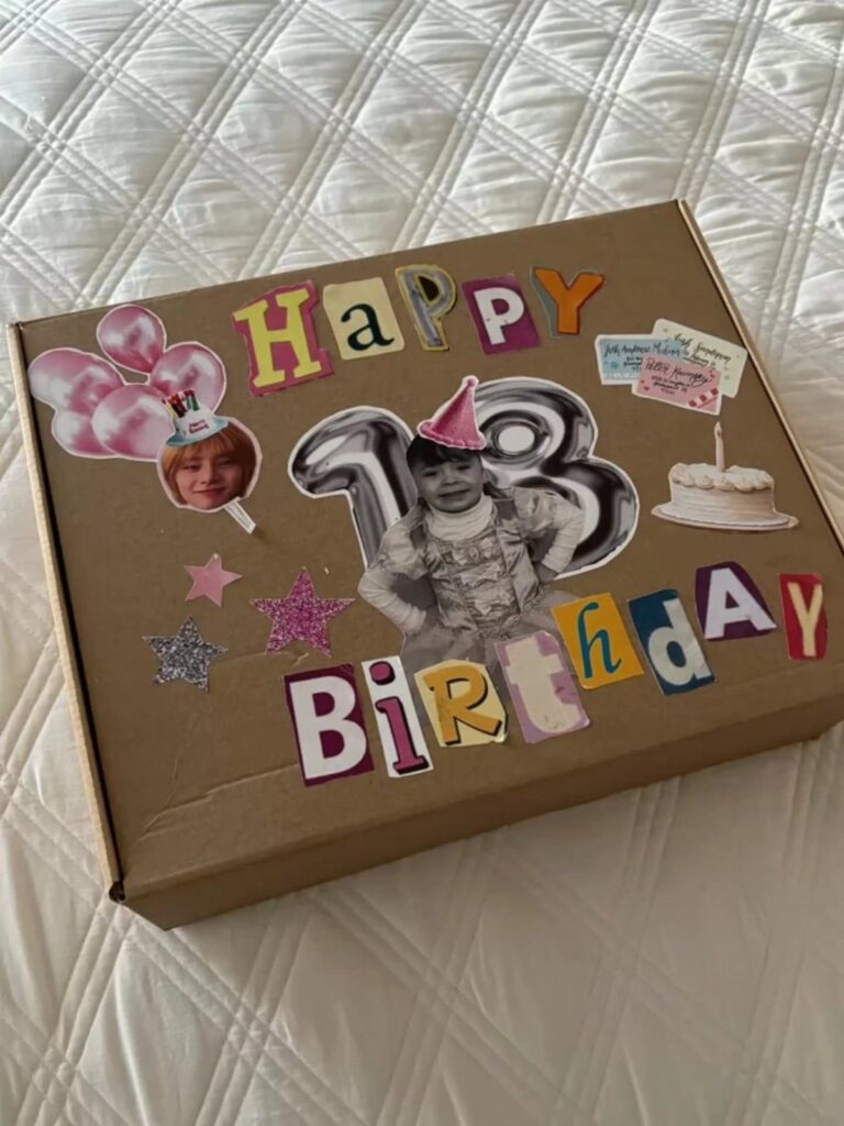 Decorated birthday gift box with colorful letters, photos, and stars on white bedding