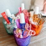 Colorful glass cups filled with beauty products and chocolates as gift sets.