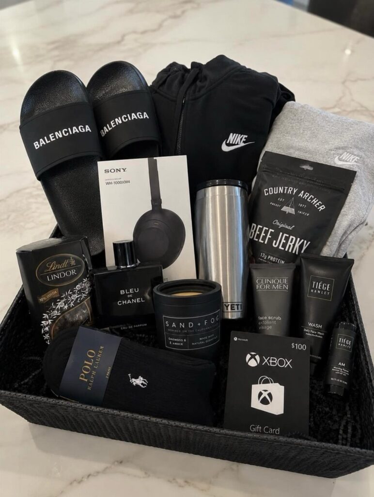 Gift basket containing luxury slides, electronics, cologne, and snacks for a man.