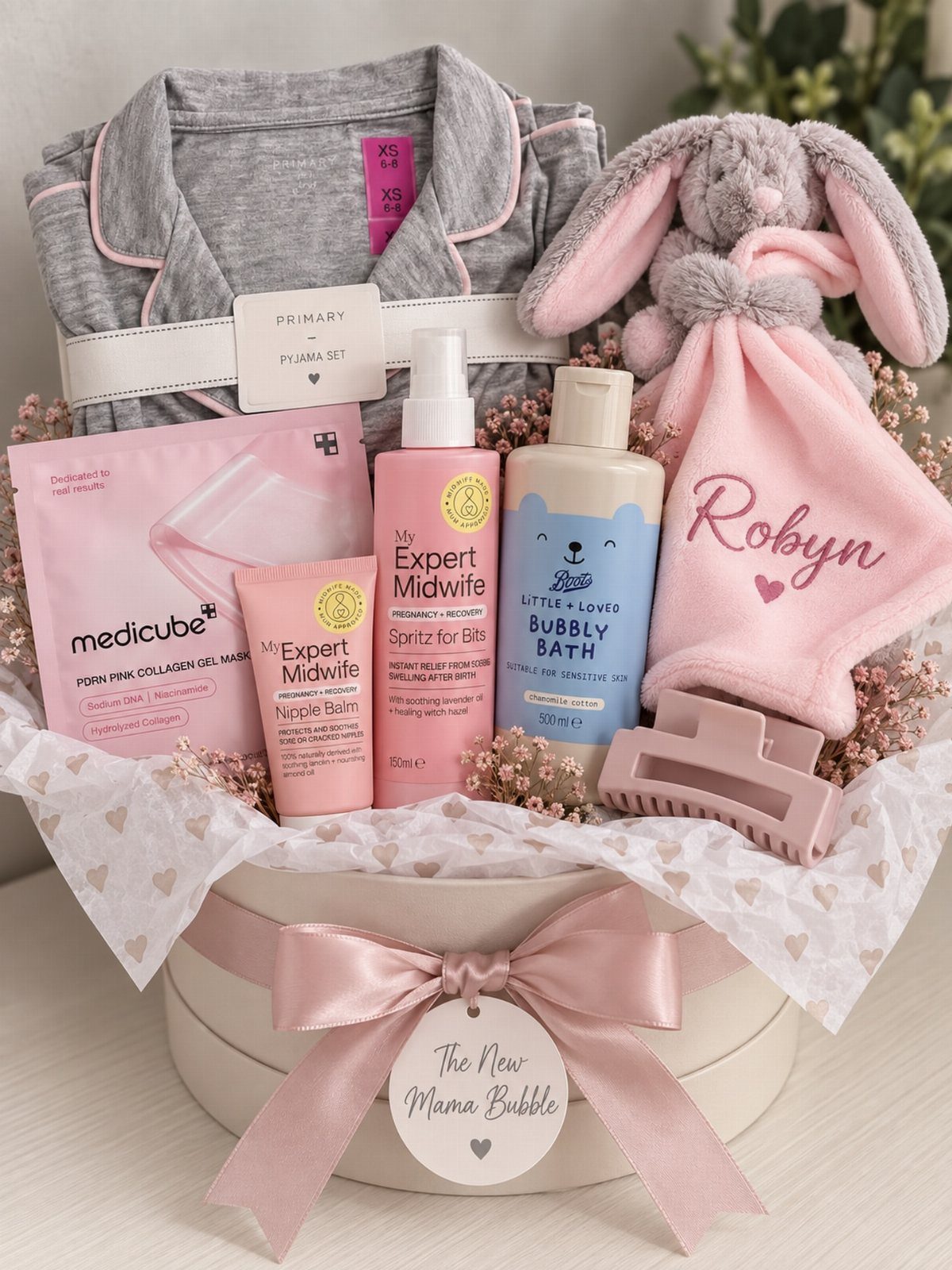 Gift basket for new mother with robe, skincare, and pink baby accessories.