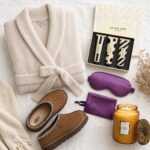Cream plush robe, brown slippers, and luxury beauty products arranged on white fabric.