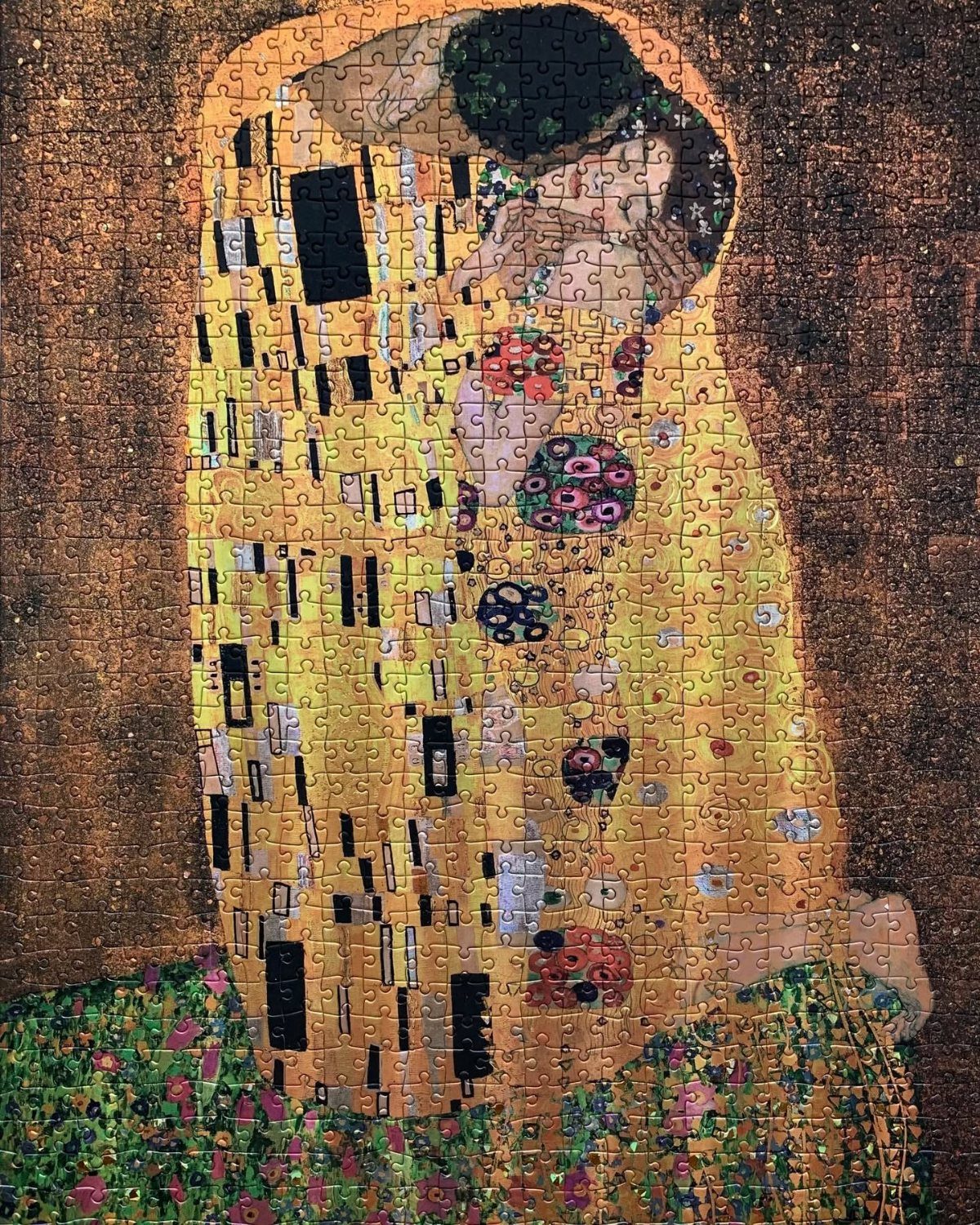 Jigsaw puzzle of Gustav Klimt's The Kiss featuring gold-patterned figures embracing.