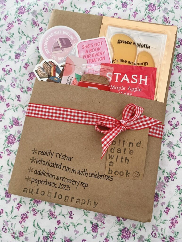 Brown paper envelope tied with red ribbon containing book-themed gifts and stickers.