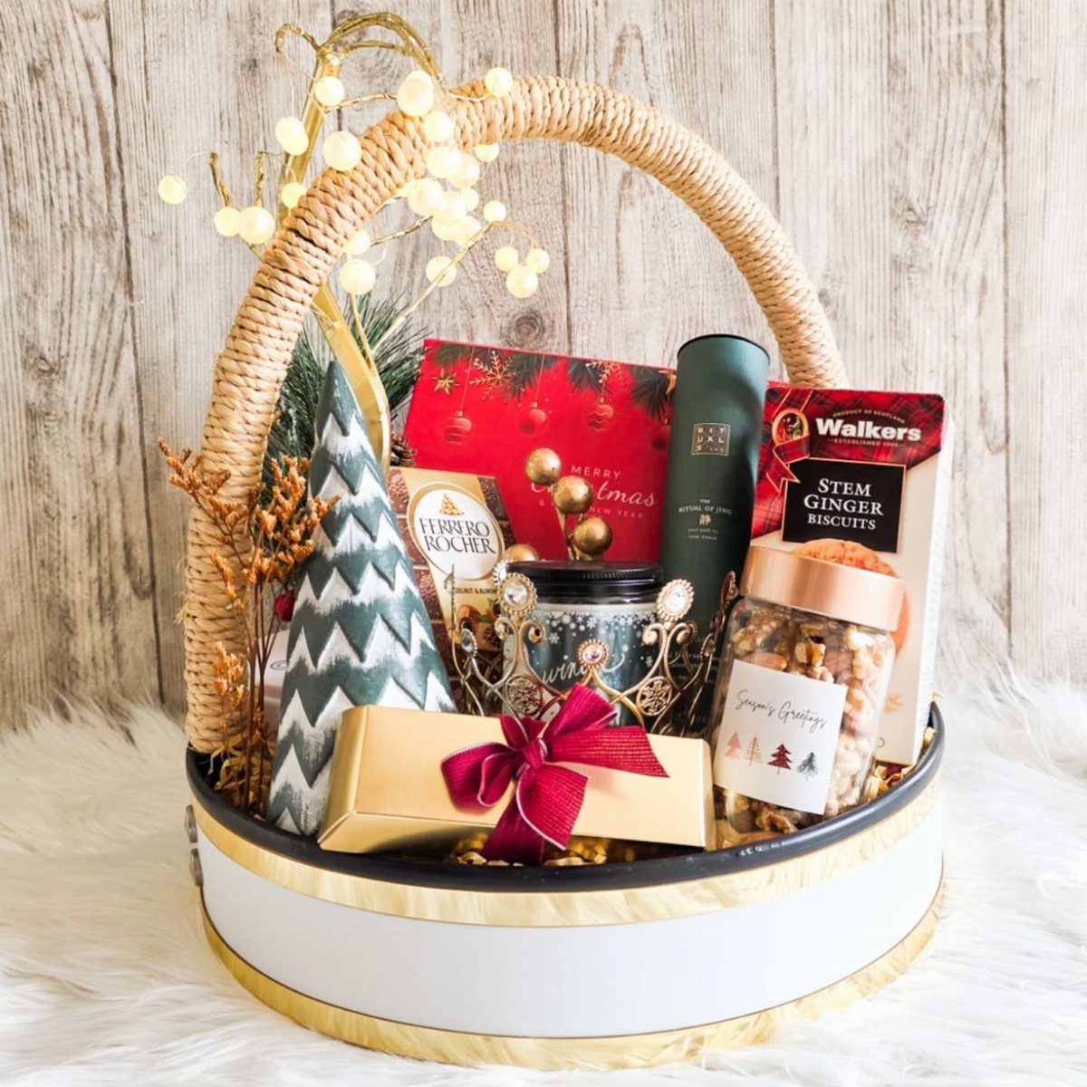 Gourmet gift basket with snacks, biscuits, and a gold gift box with red bow.