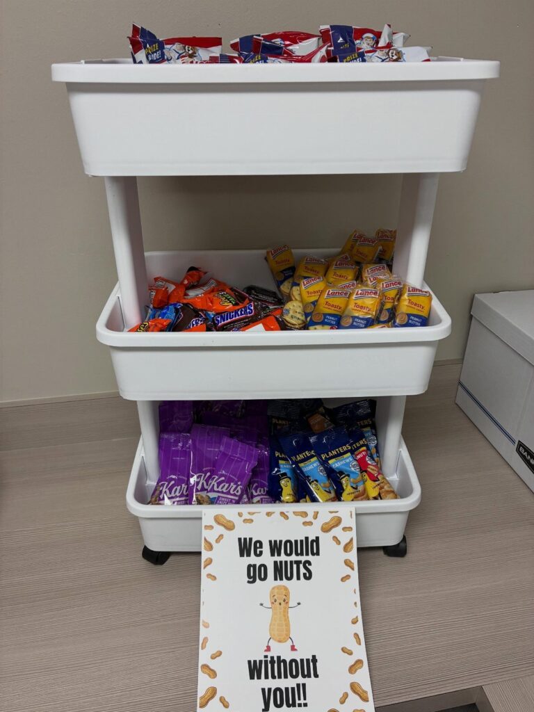White rolling cart filled with snacks and a punny peanut appreciation sign.