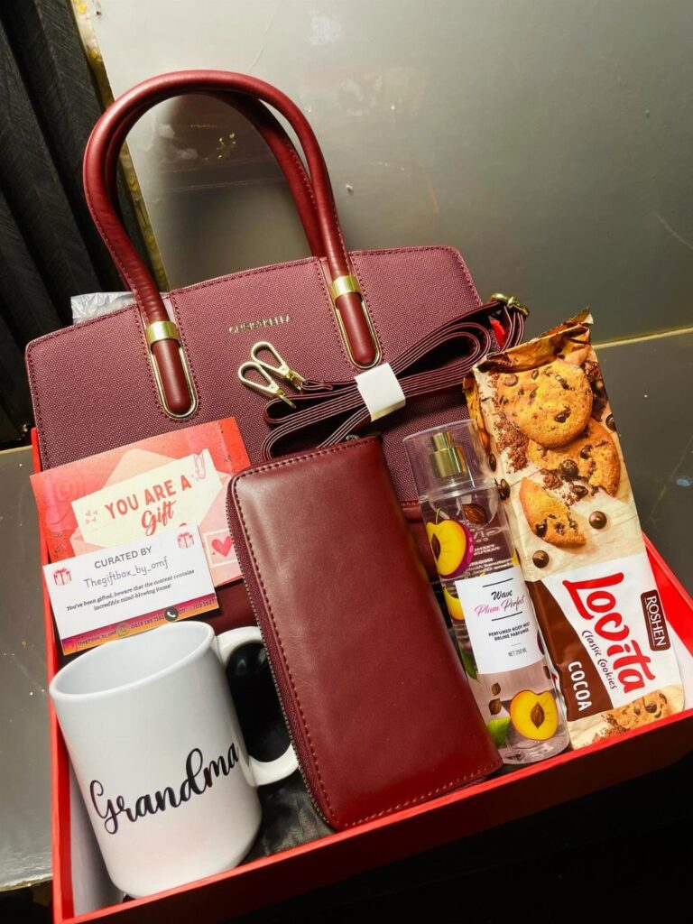 Gift tray with burgundy handbag, red wallet, Grandma mug, and chocolate cookies.