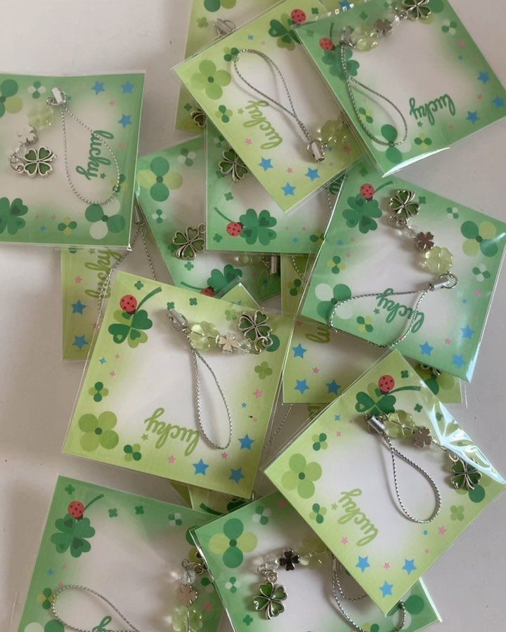 Silver four-leaf clover bracelets on green lucky cards in clear plastic packaging.