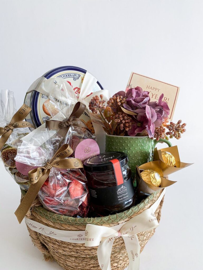 Wicker gift basket containing treats, flowers, and a Happy New Year card.