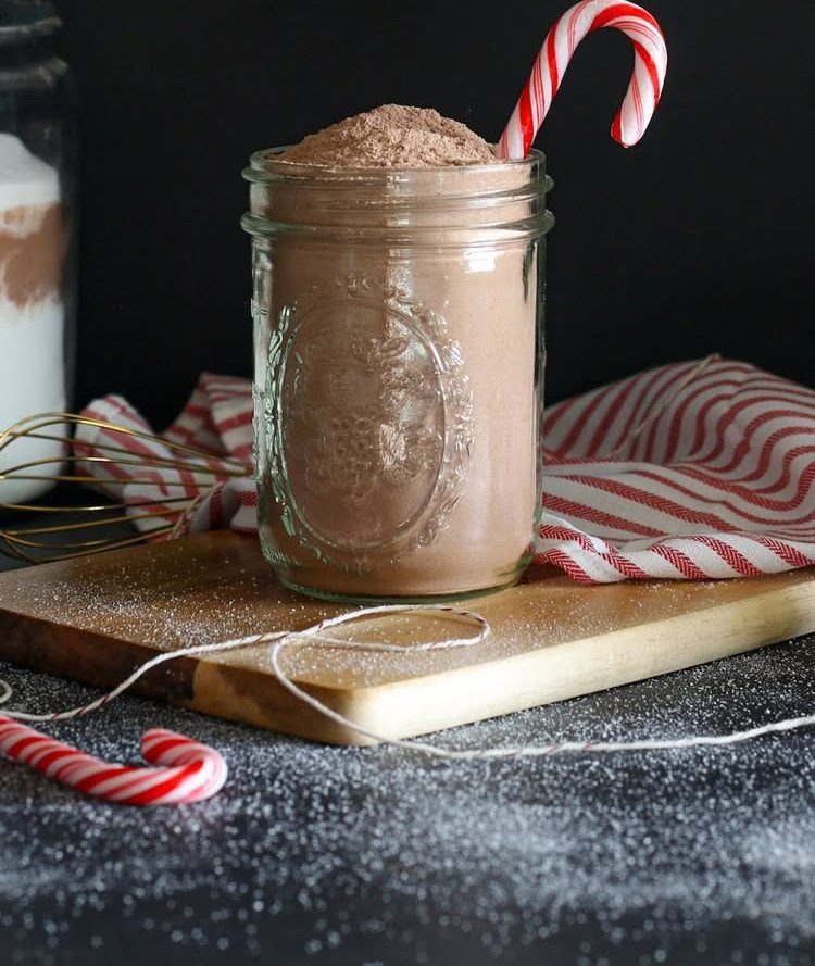 Glass mason jar filled with hot cocoa mix and a candy cane garnish.