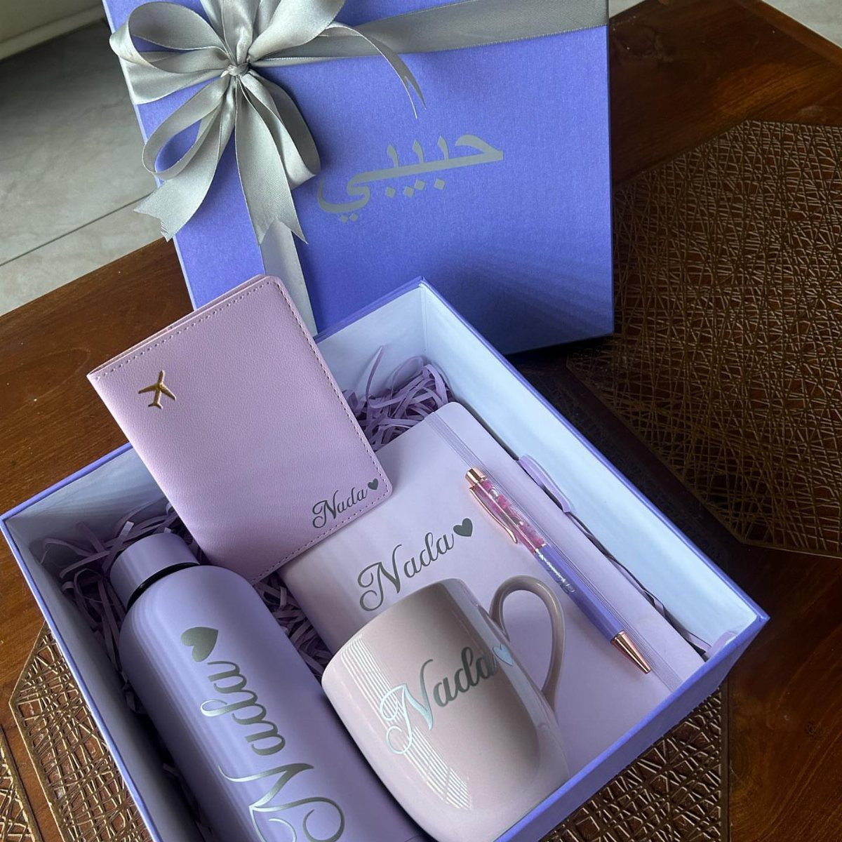 Purple personalized gift set with name Nada on a mug, bottle, and notebook.
