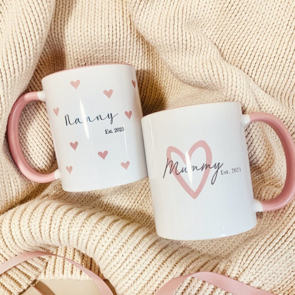 Two white personalized mugs for Nanny and Mummy on a cream knit blanket.