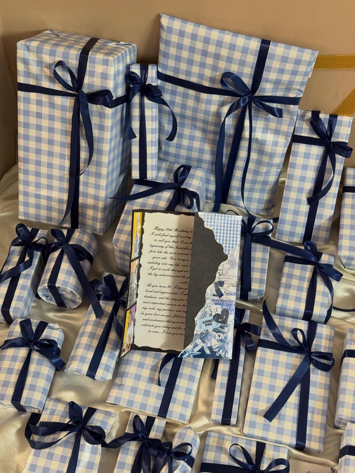 Wrapped gift boxes in blue gingham paper with dark blue ribbons and a letter.