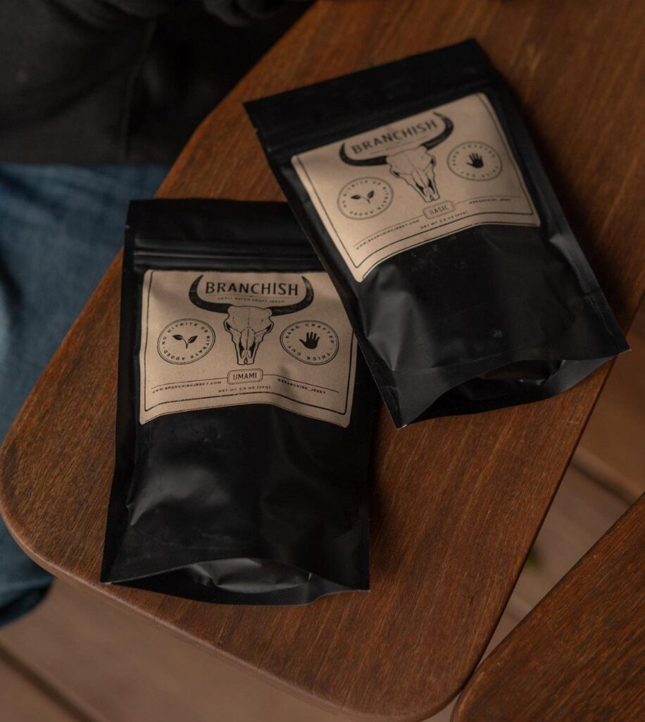 Two black pouches of beef jerky on a brown wooden table surface.