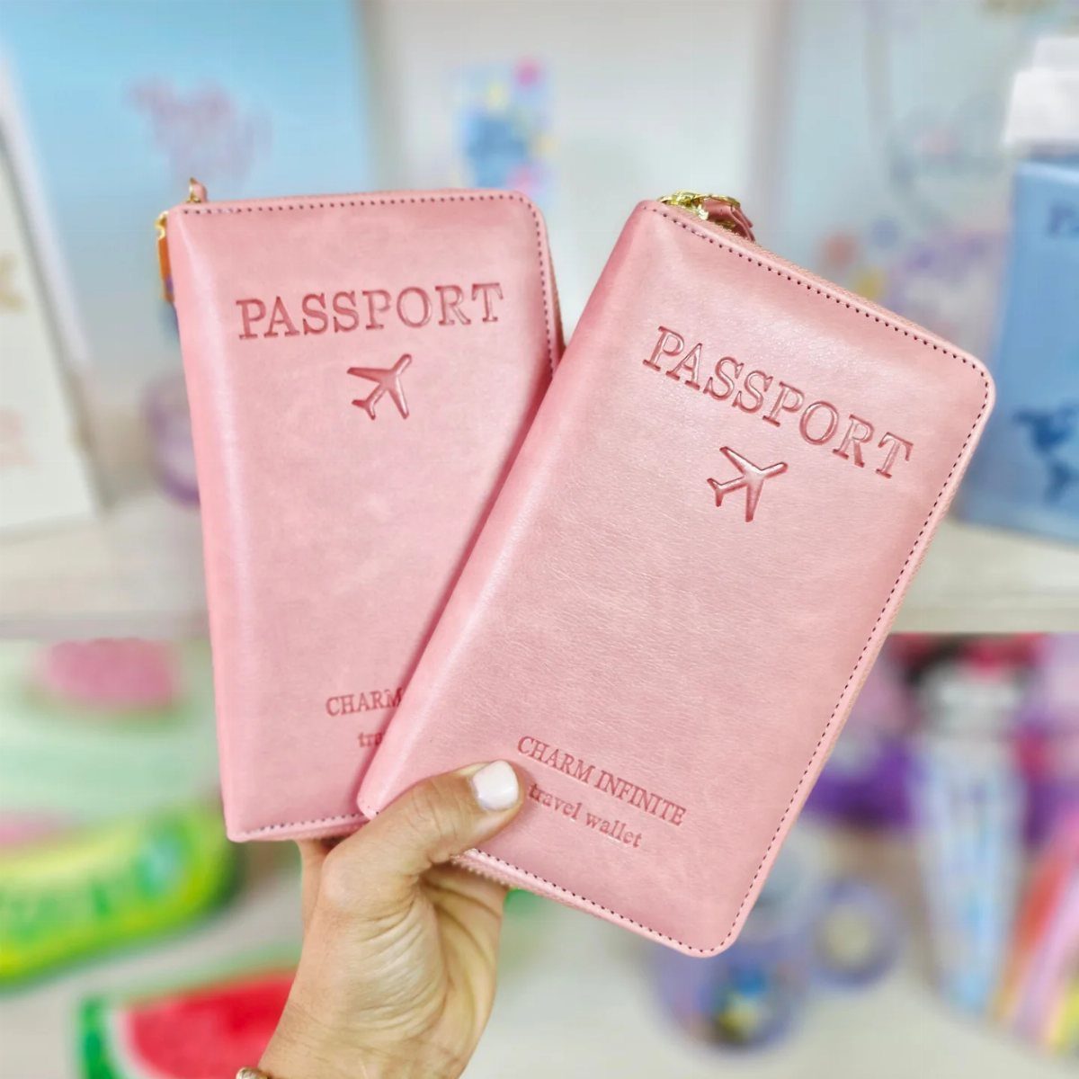 Two pink leather travel wallets with passport embossing held by a hand.