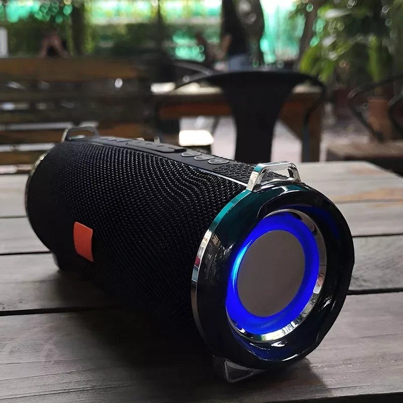 Black portable Bluetooth speaker with a glowing blue light ring on a wooden table