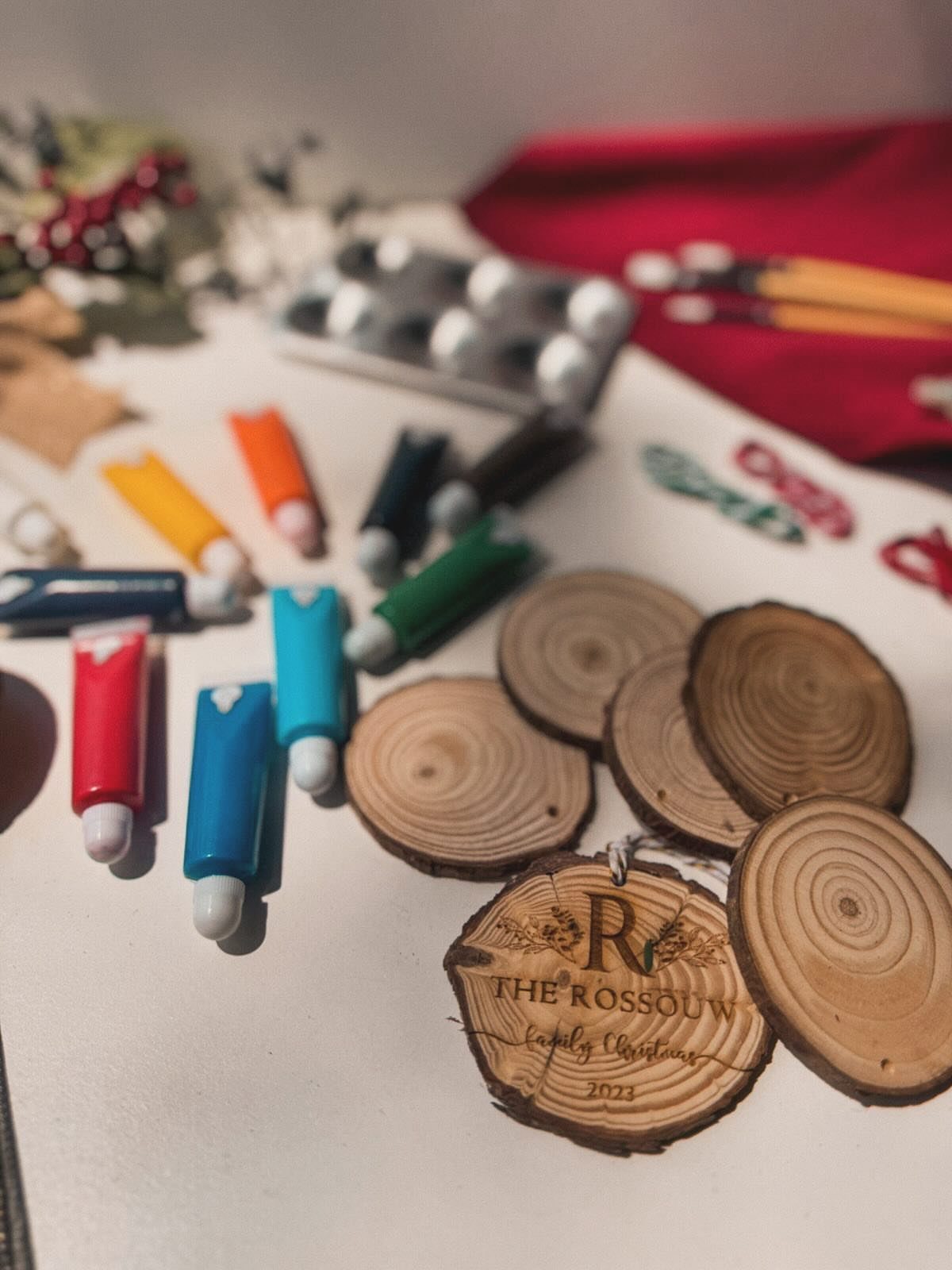 Wooden ornament slices and colorful paint markers for a DIY Christmas craft project.