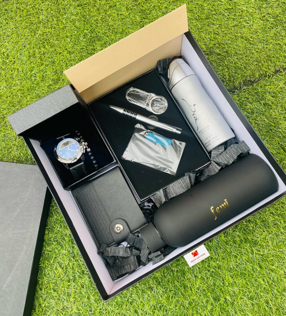 Gift box for men with watch, wallet, bottles, and pen on green grass
