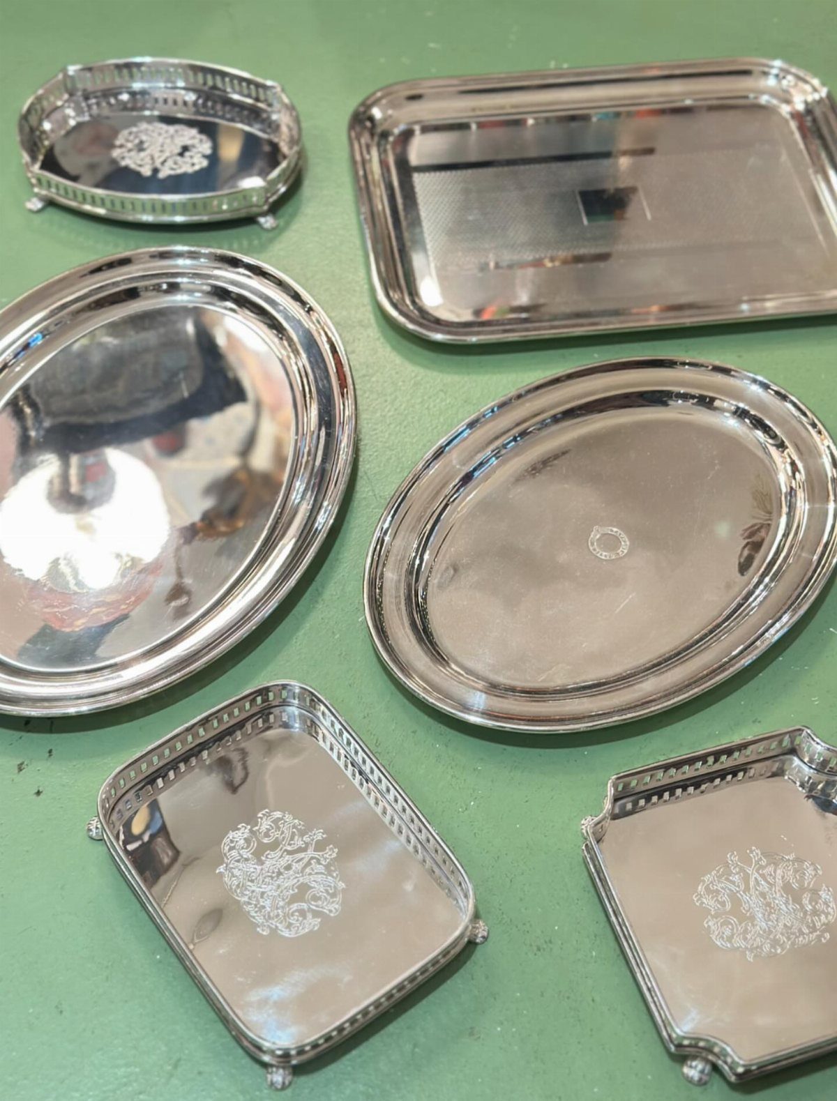 Silver metal trays of various shapes and sizes on a green surface.