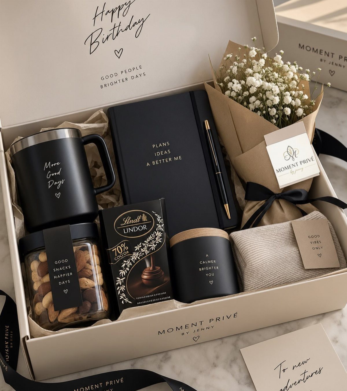 Curated gift box for men with black accessories, chocolates, and white flowers.